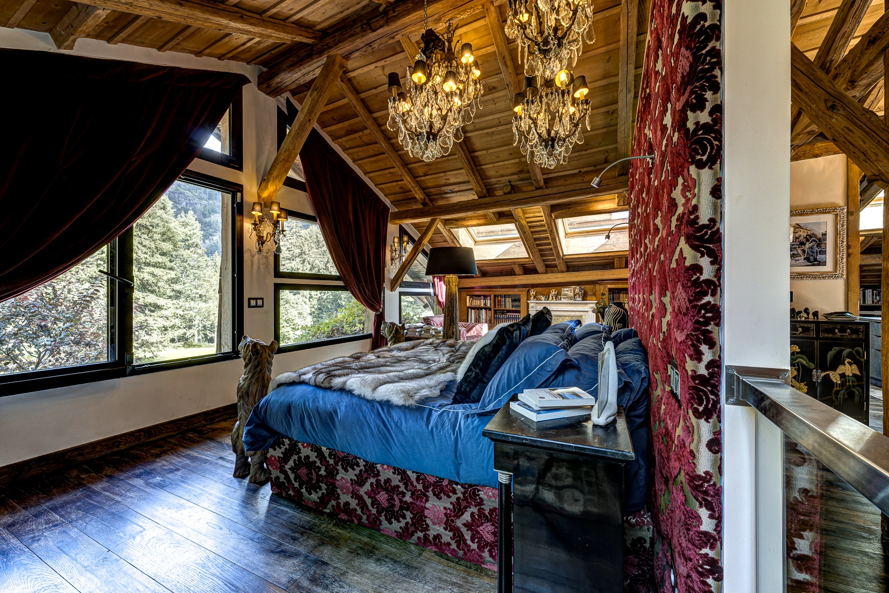 Photo vue de derrière du lit sous les toits, lustre, tête de lit brodée, rideaux en velours et couverutre en fourrure
