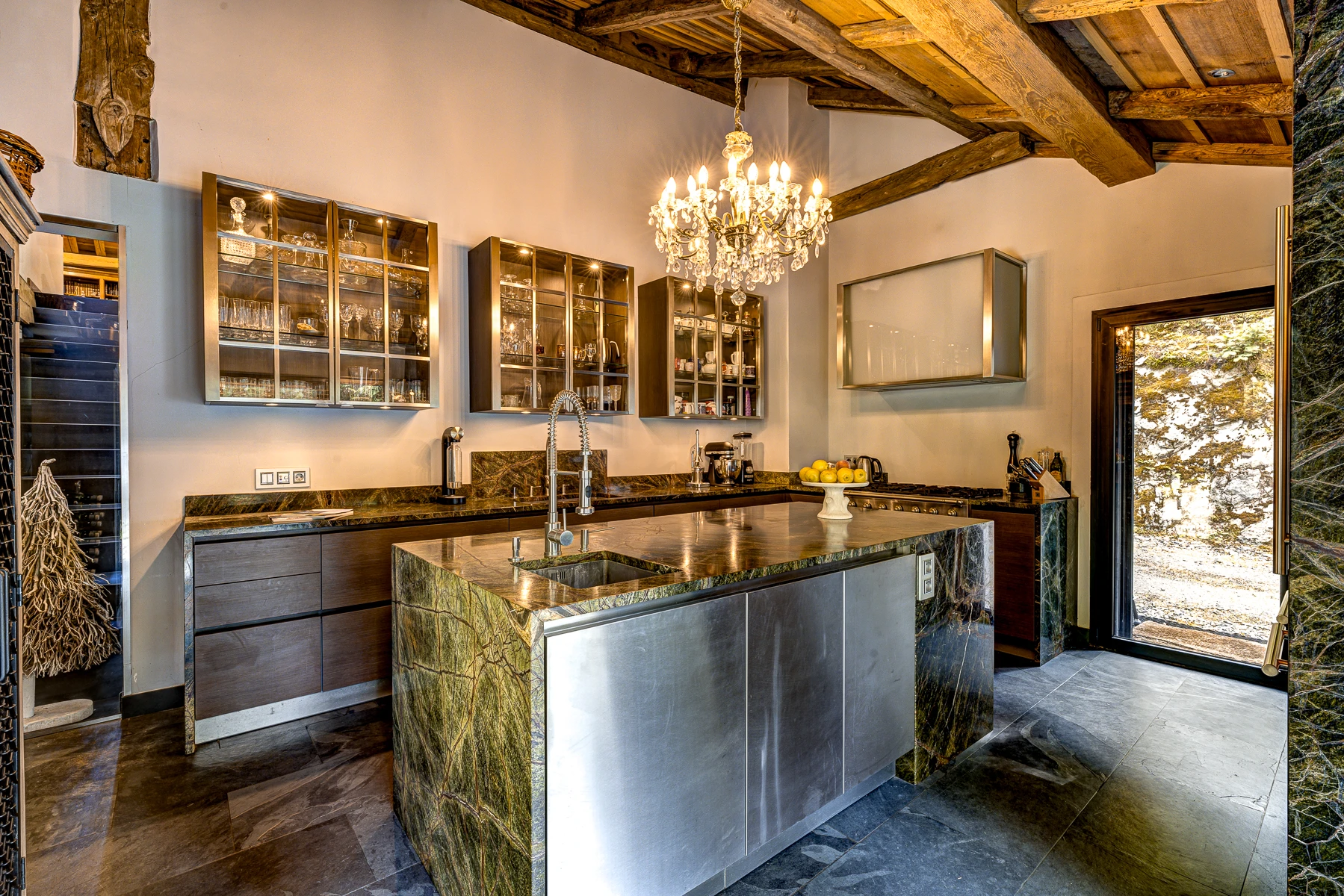 Photo de la cuisine, centrée sur l'îlot. Deux éviers, hote, four, micro-ondes, cave à vin et machine à café