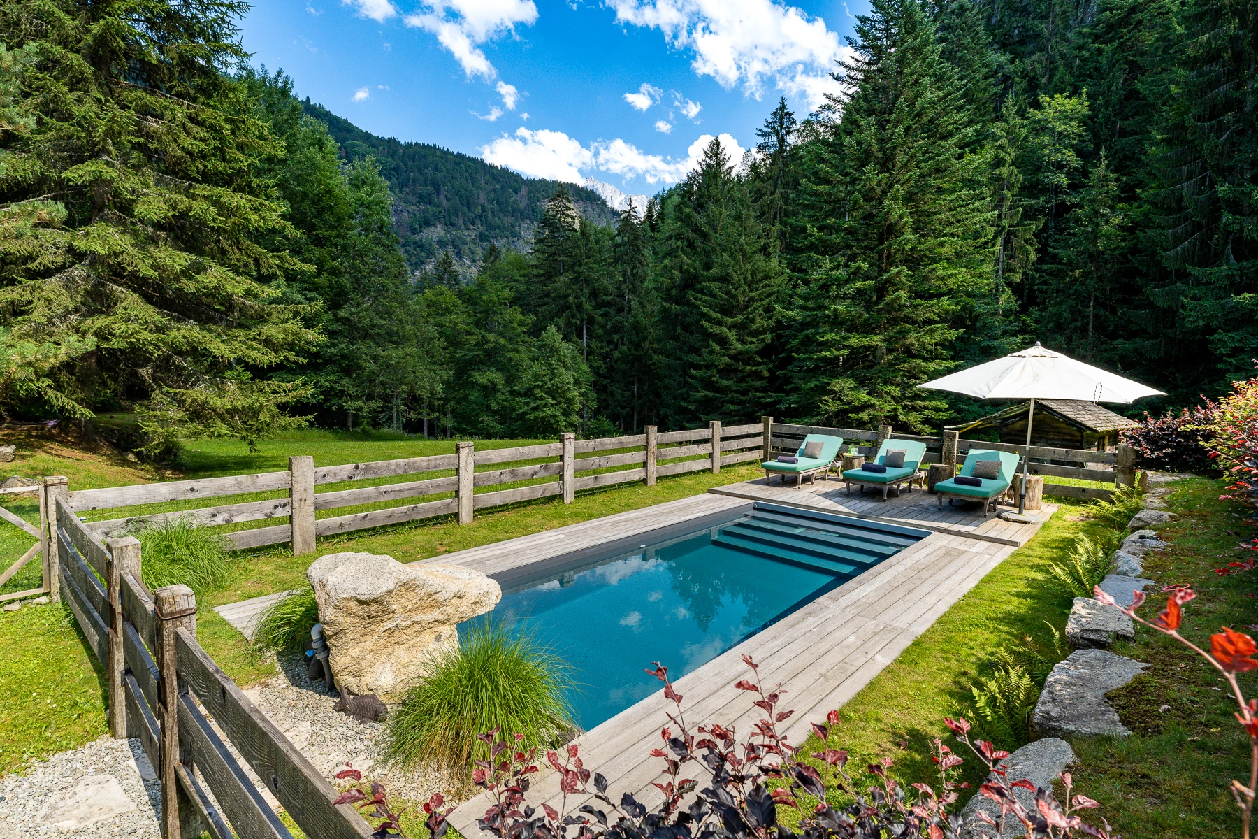 Photo de la piscine extérieure chauffée, avec ses transats et la vue sur les montagnes.