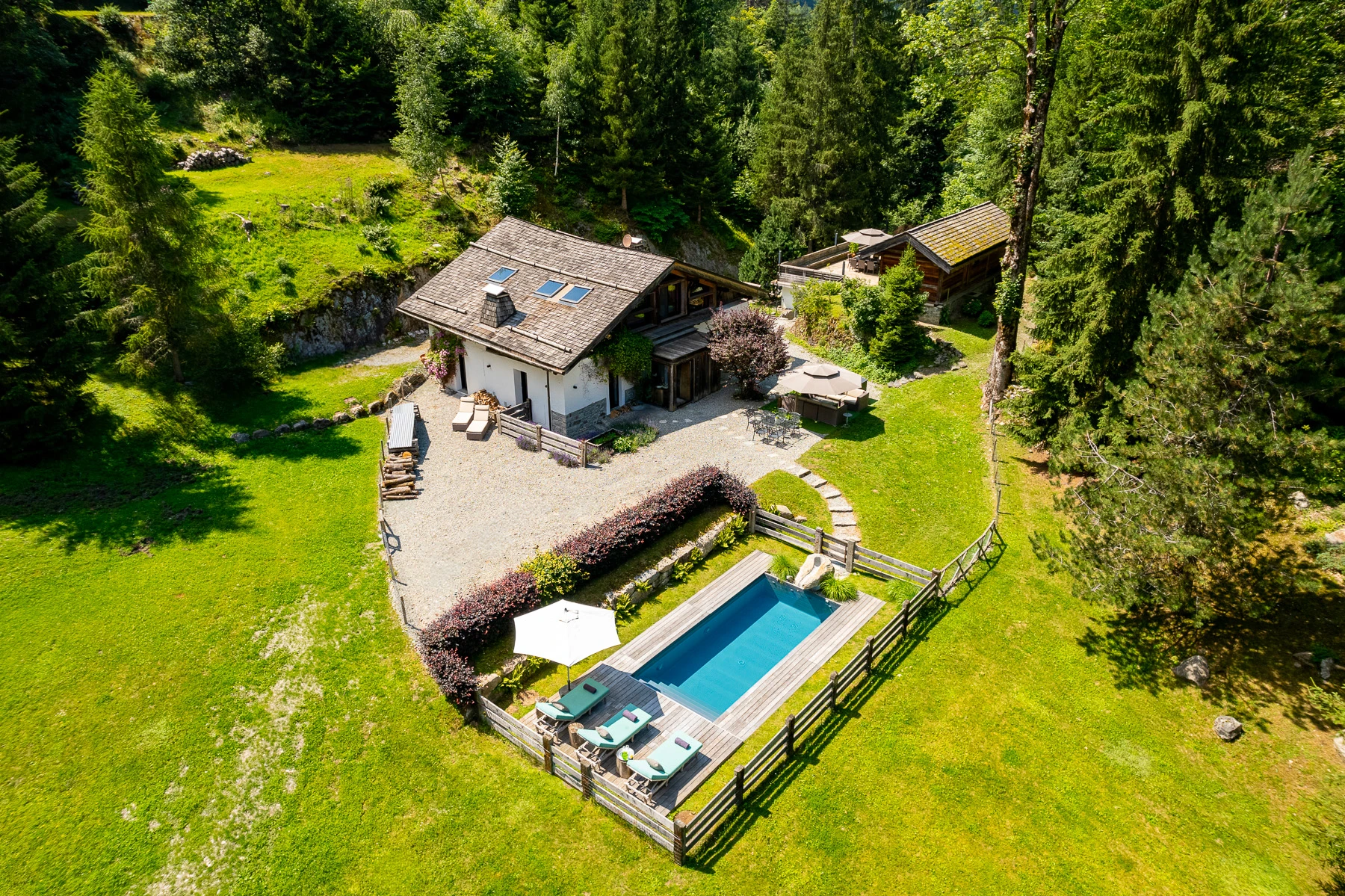 Photo de la maison principale vue de drone, avec son jardin, sa piscine chauffée et ses aménagements pour l'exérieur.