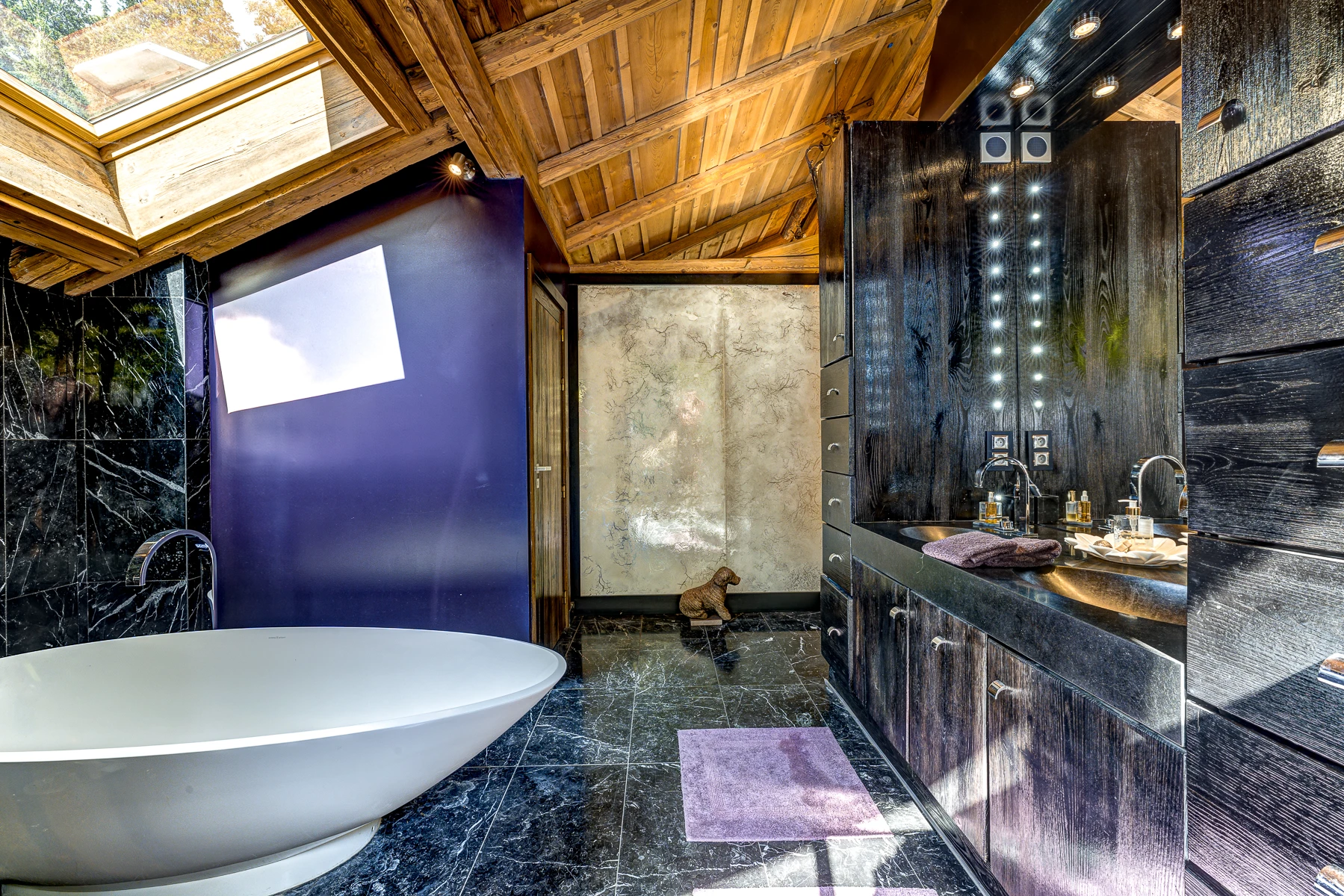 Photo de l'autre angle de la salle de bain avec ses toilettes, deux lavabos, grand miroirs, confort luxueux